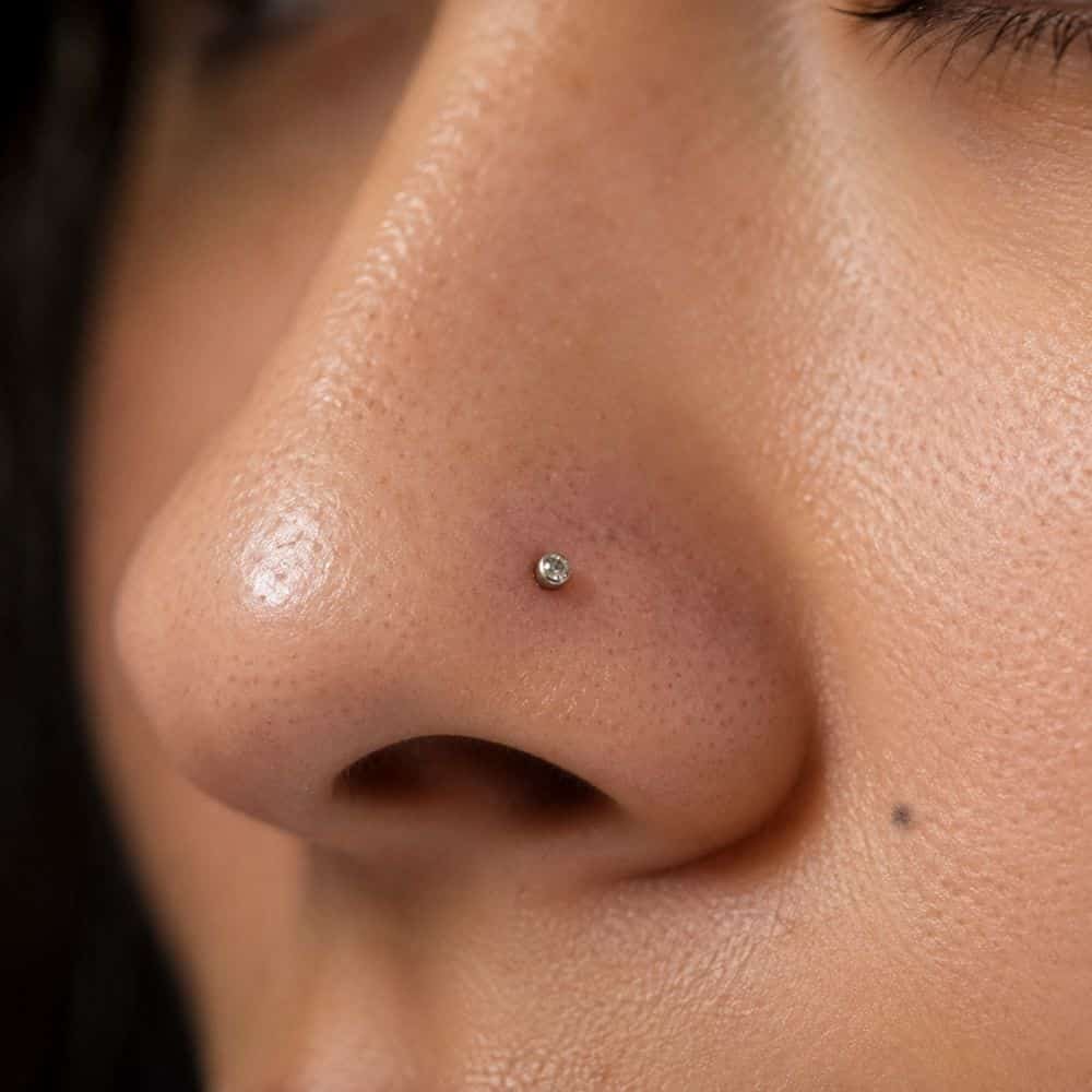Perforación de nariz nostril con joya de titanio en piel real
