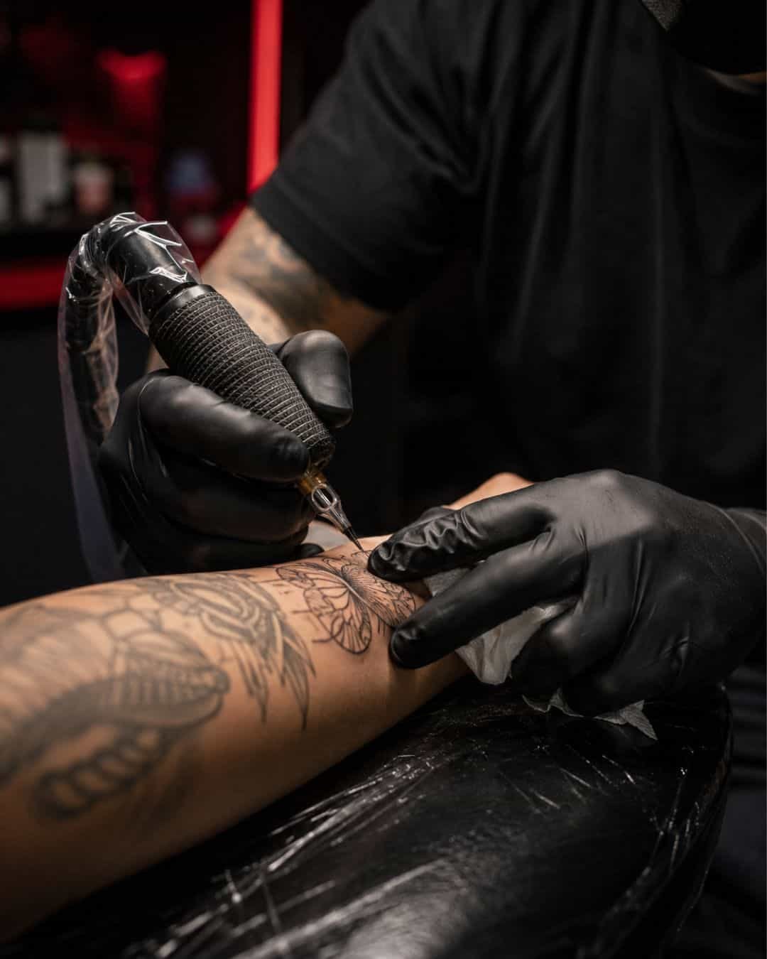 Tatuador con guantes trabajando un tatuaje en un estudio de Coacalco con aguja estéril